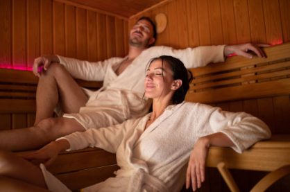 Perfect looking mid adult couple sitting in sauna and enjoying their time together. They are wearing bathrobes and they are looking happy